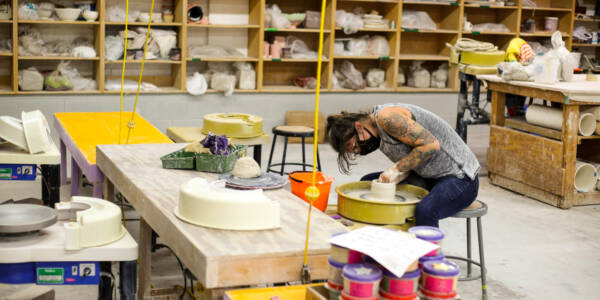 woman molding clay on the wheel in the clay studio at VisArts