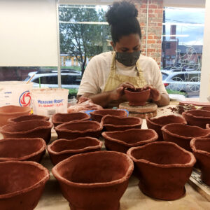 Ceramicist Kourtenay Plummer pictured with dozens of clay bowls in VisArts clay studio